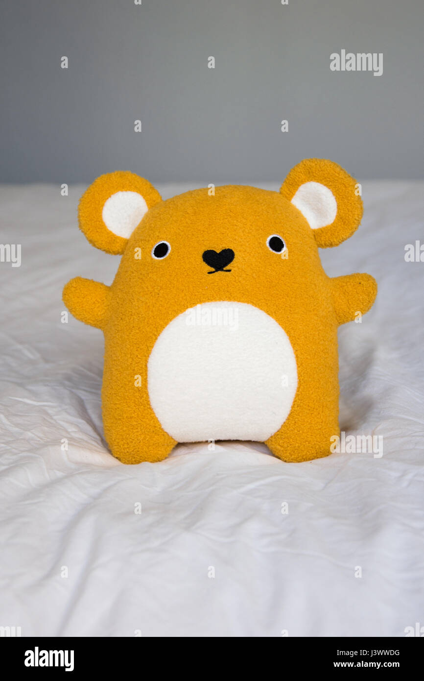 Cute little orange Teddy Bear sitting on a bed Stock Photo Alamy
