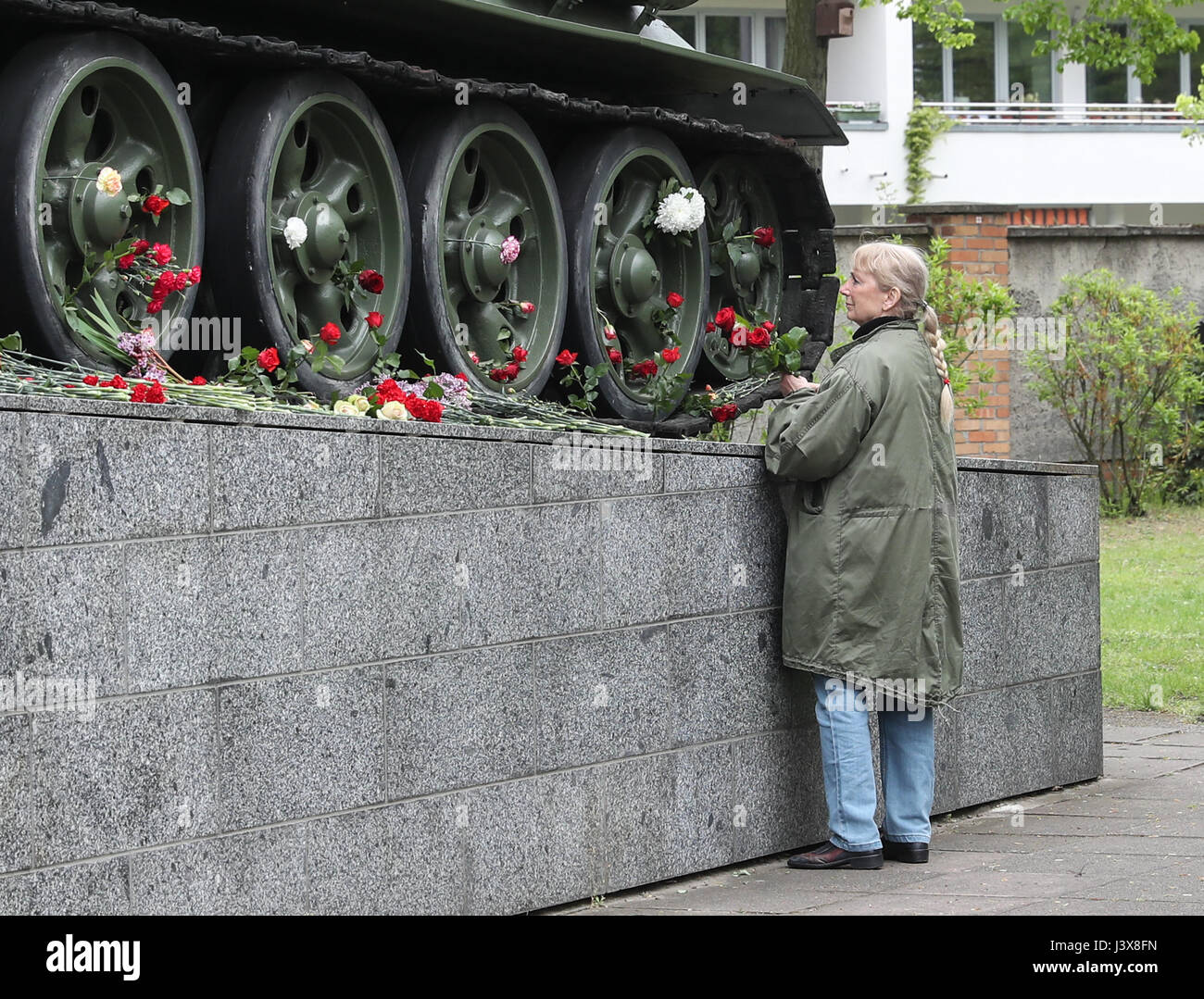 Berlin, Germany. 8th May, 2017. A woman presents flowers near a tank model during a series of memorial activities to commemorate the 72nd anniversary of the end of World World II in Europe, known as Victory in Europe Day at German-Russian Museum in Berlin, capital of Germany, on May 8, 2017. Credit: Shan Yuqi/Xinhua/Alamy Live News Stock Photo
