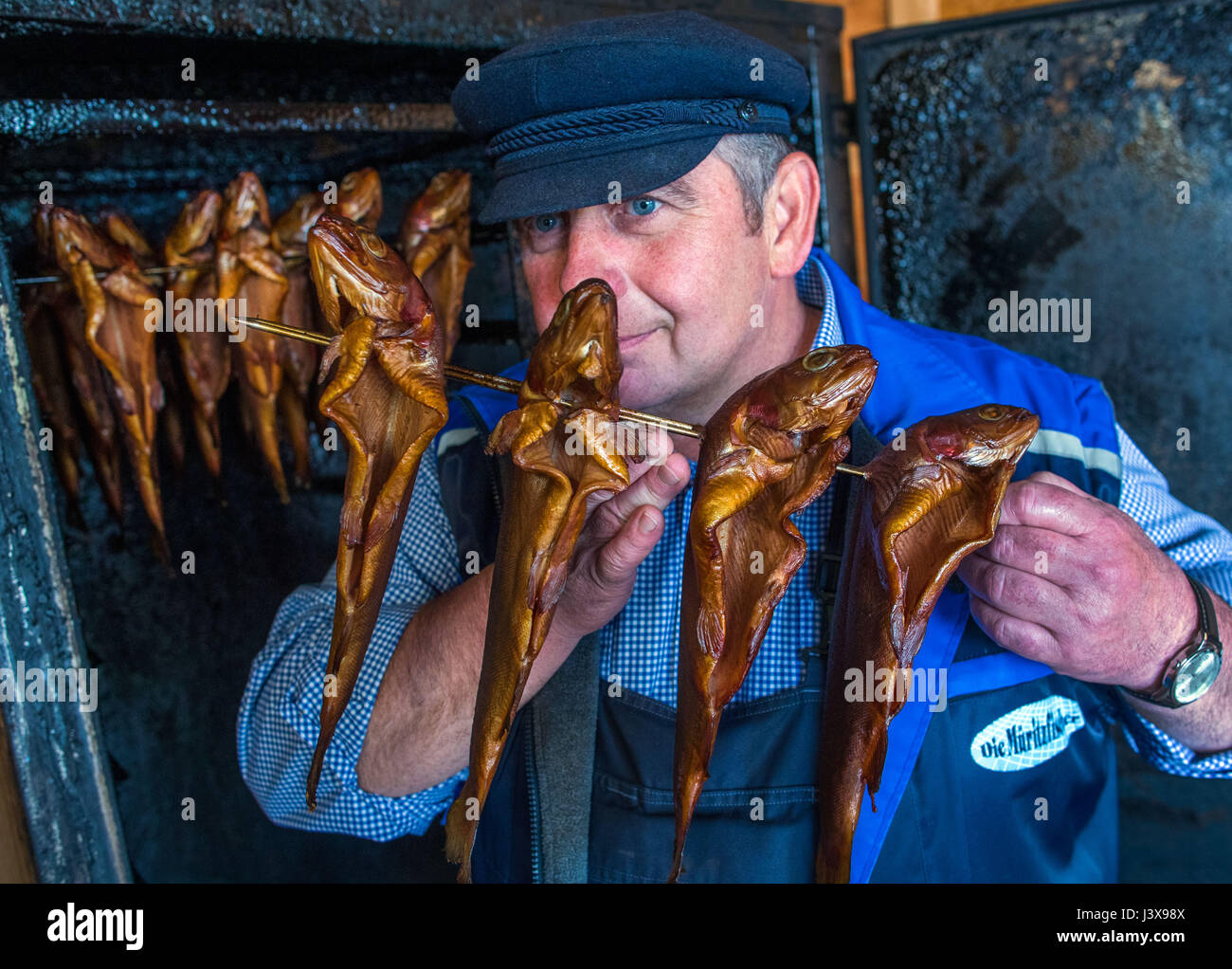 Vipperow, Germany. 4th May, 2017. Inland fisher Guenter Zillmann retrieves freshly smoked char from the oven at the fish farm at the Mueritz in Vipperow, Germany, 4 May 2017. The fish farm is part of the largest inland fishery in Germany: Fishery Mueitz-Plau GmbH. Besides the tradition fishery and the breeding of fish, modern aqua culture is also part of the business. The fishery, founded in 1990 from the former production cooperative (founded 1952) holds more than 30.000 hectars of water. Photo: Jens Büttner/dpa-Zentralbild/dpa/Alamy Live News Stock Photo