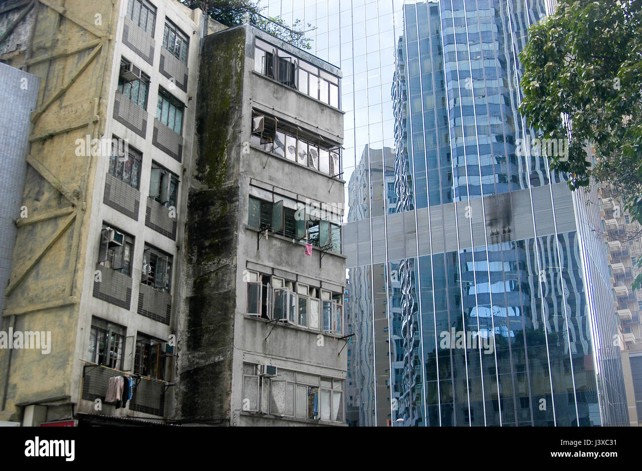 Old, grungy cement apartment buildings set against a glass skyscraper in Hong Kong. Stock Photo