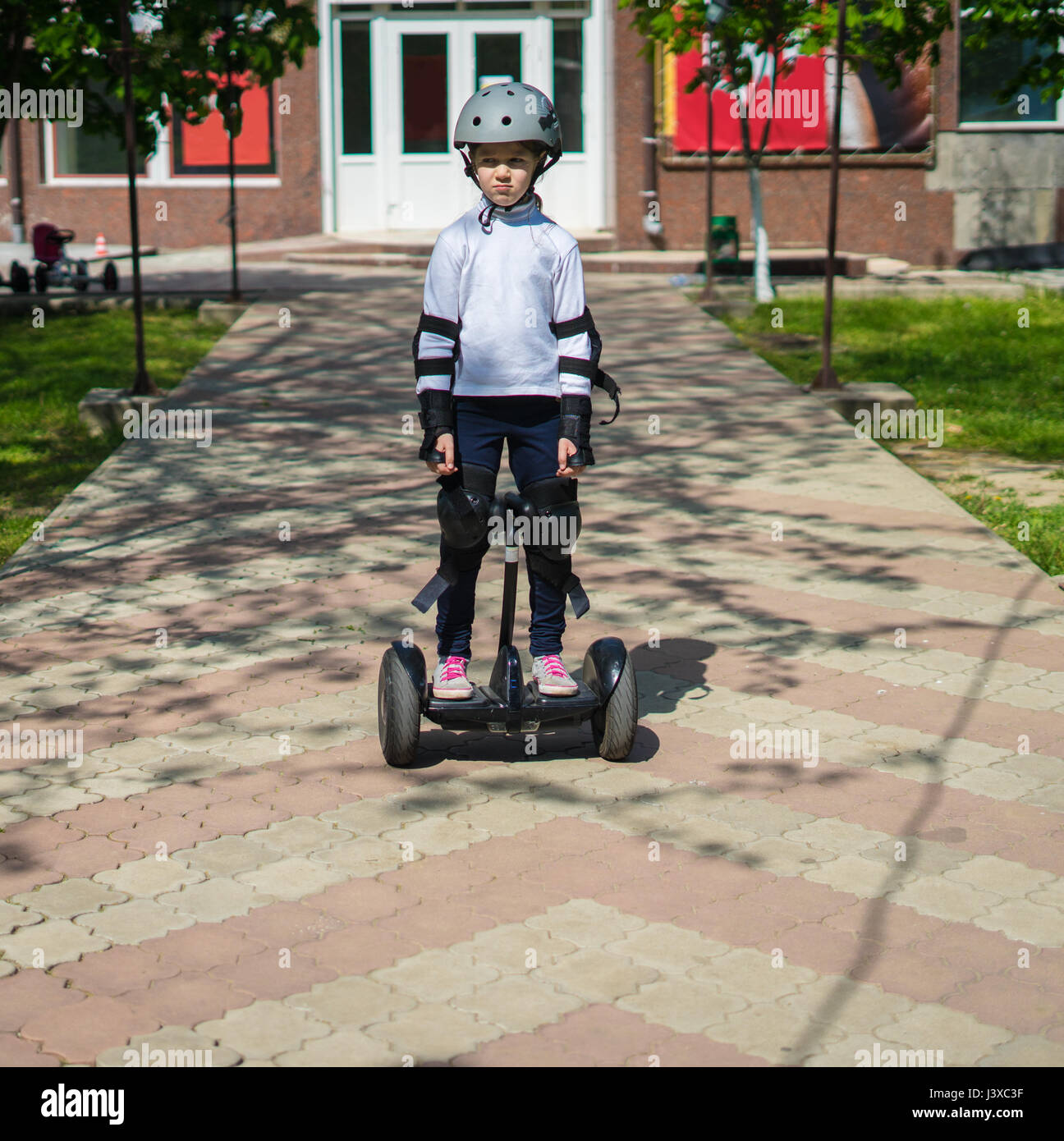 Small sad girl riding electric mini hoverboard Stock Photo