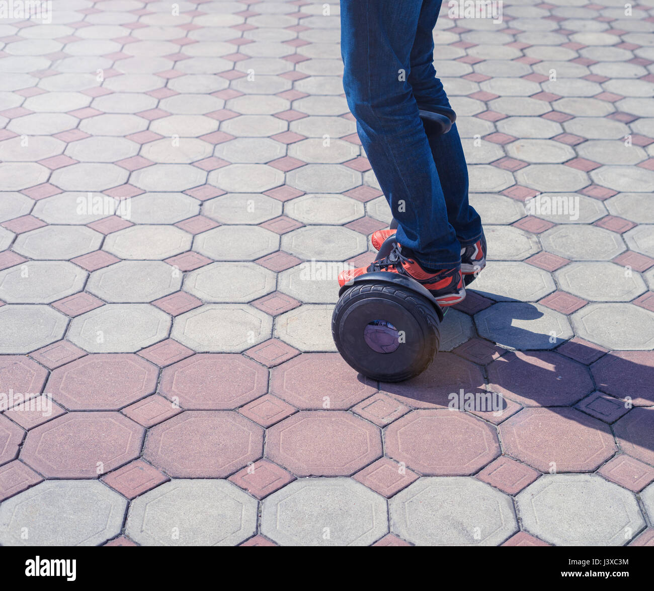 Man's legs in orange sneakers ride gyroscooter or hoverboard Stock Photo