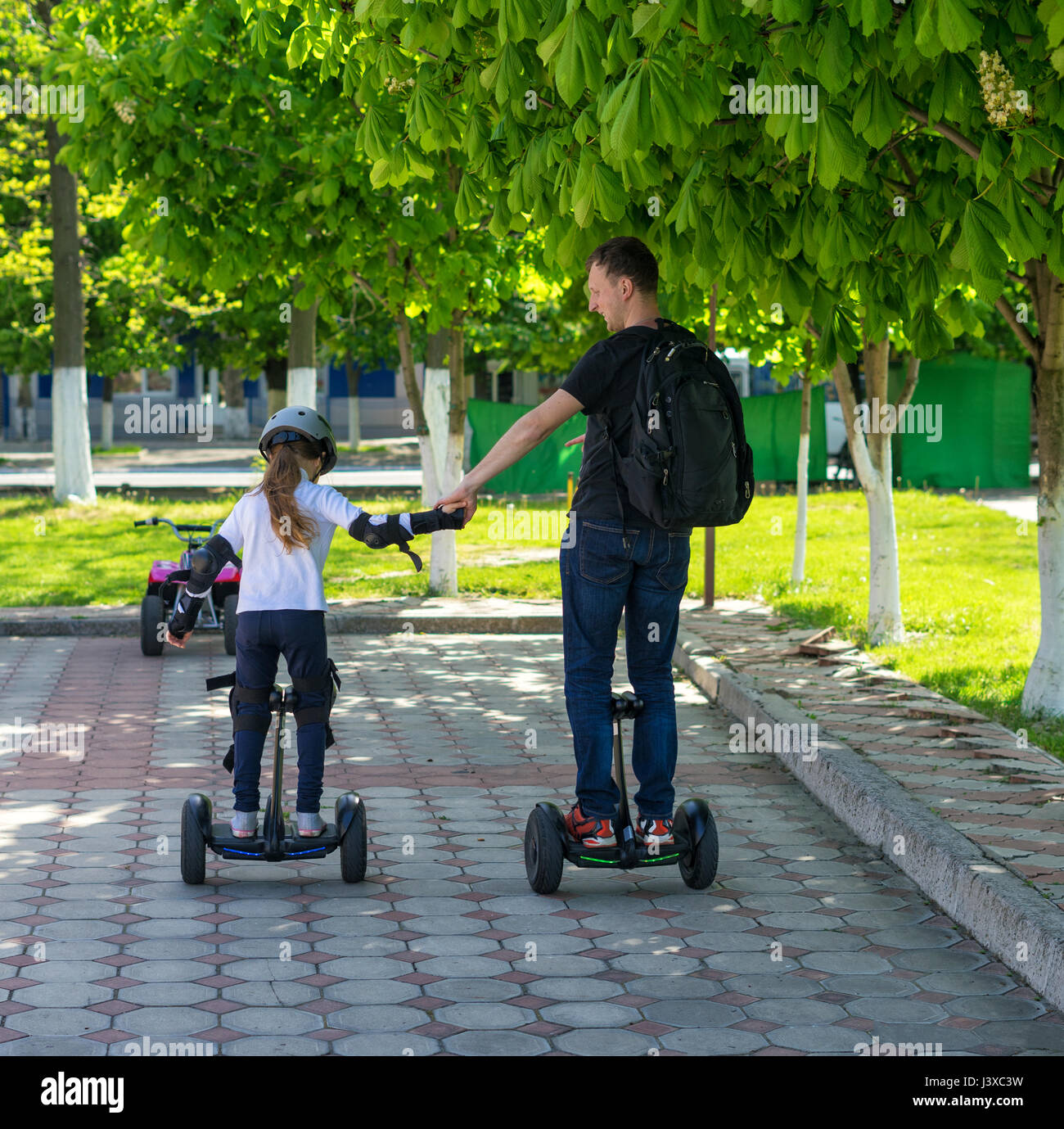 Young father and daughter riding electric mini hoverboard in park Stock Photo