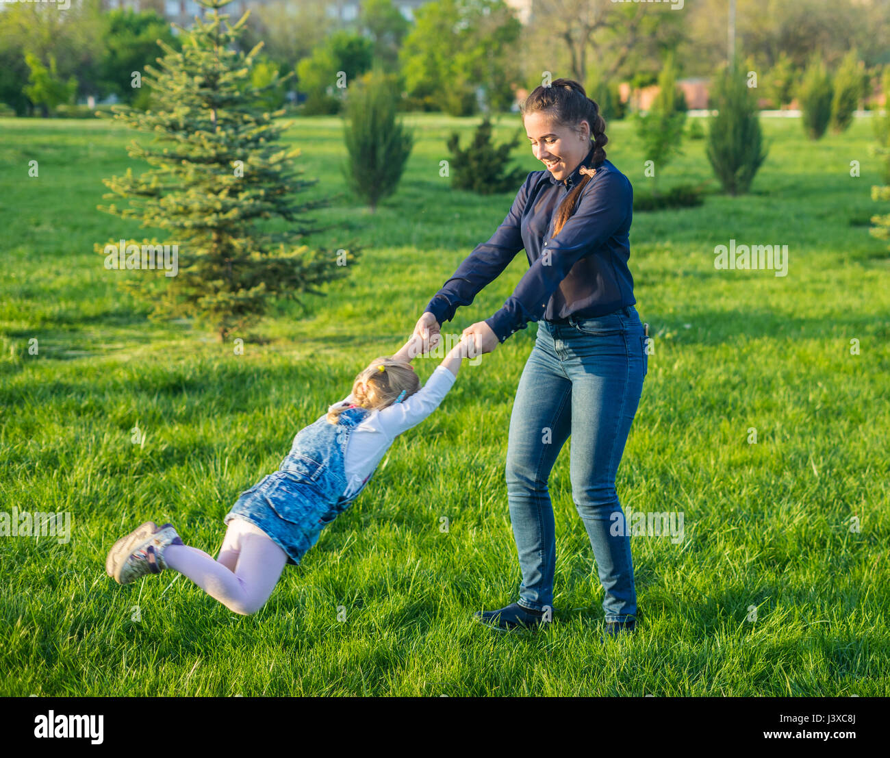 Beautiful mother lifts girl and begins turning her around Stock Photo