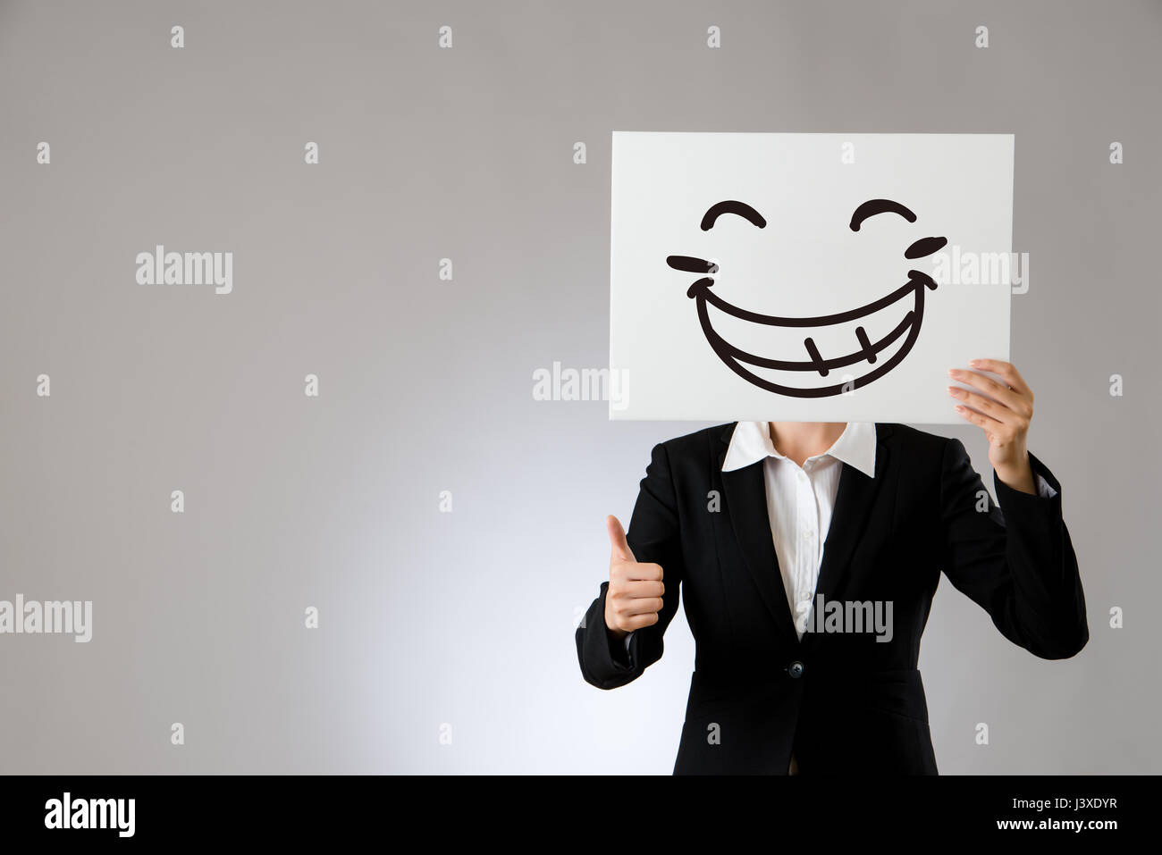 laughing business office lady holding blank white board with thumbs up hand gesture. isolated on gray background. business office company concept. Stock Photo