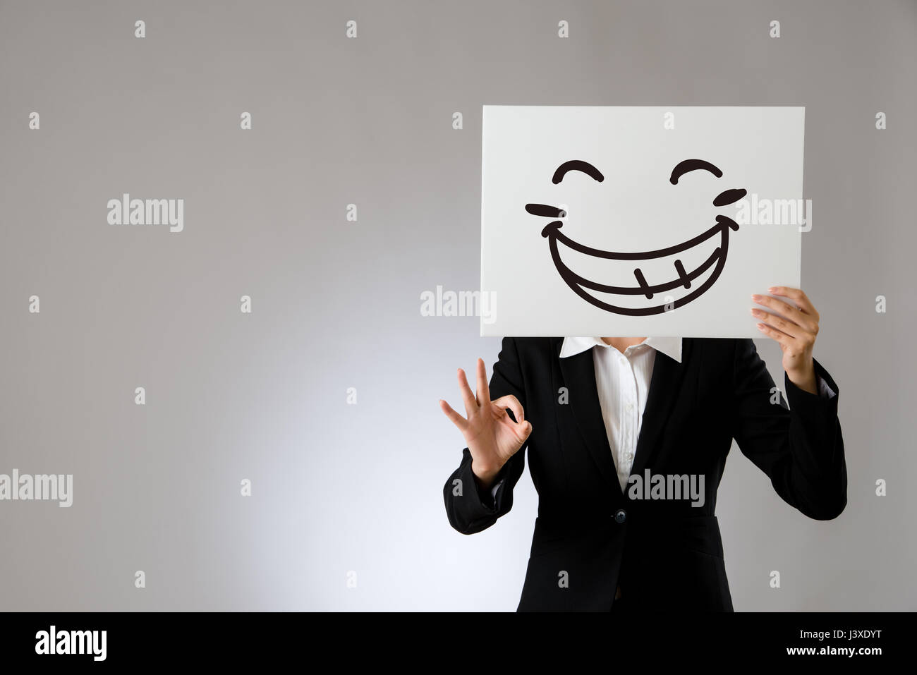 laughing business office lady holding blank white board with ok hand gesture. isolated on gray background. business office company concept. Stock Photo
