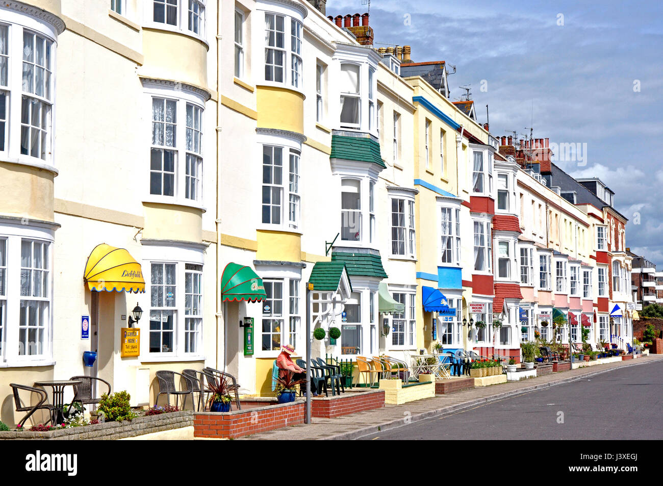 Georgian period seafront hotels -Weymouth Dorset white with pastel coloured bow windows - door canopies - chairs for residents - sunshine  blue sky Stock Photo