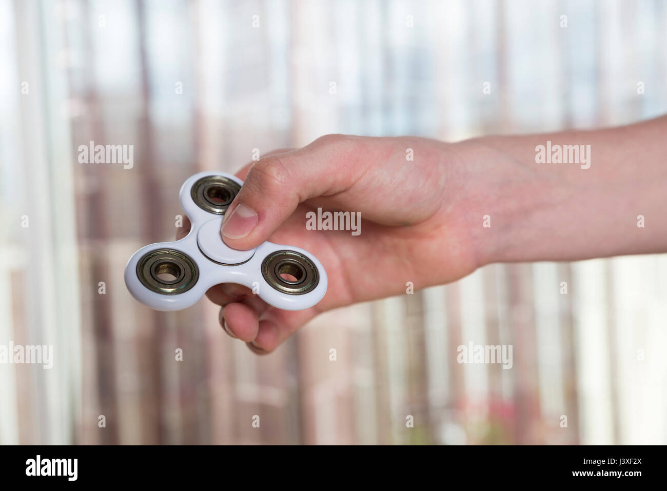 Young boy playing with fidget spinner toy to relieve stress at home Stock Photo