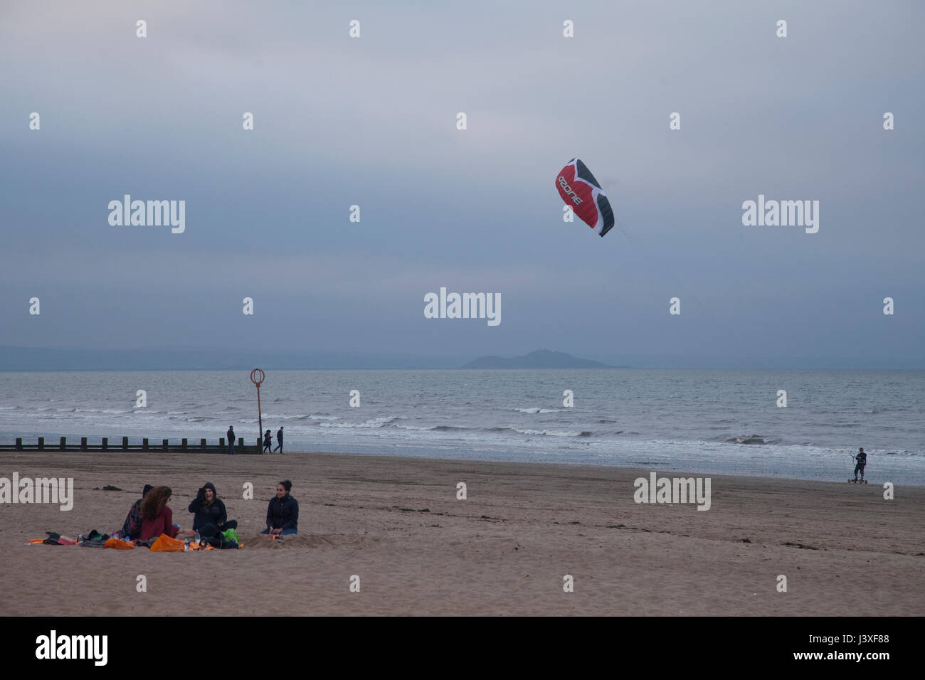 People sitting around the fire on Portobello beach in sunset. Edinbrugh