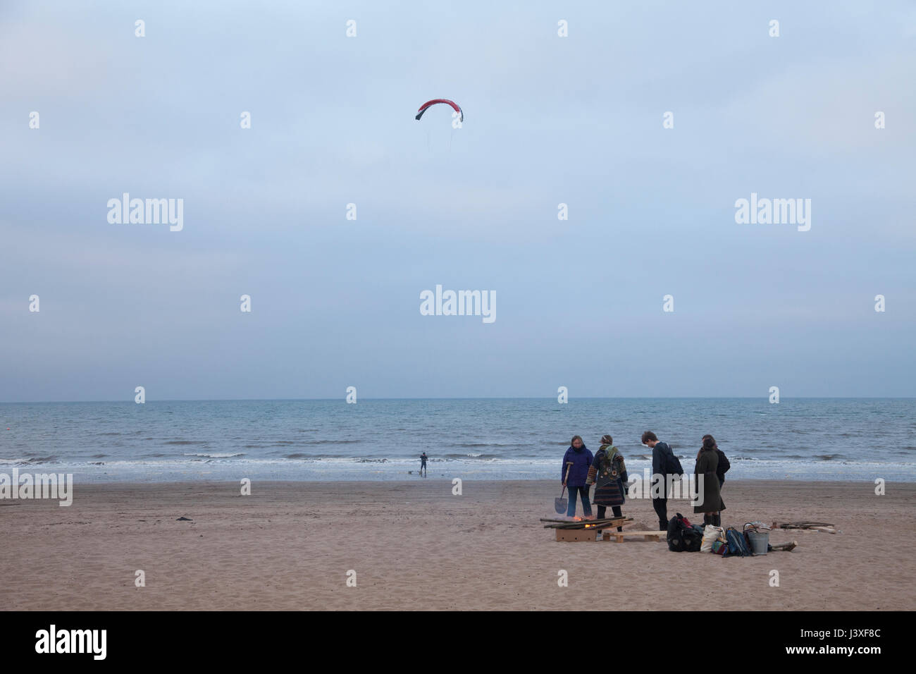 People sitting around the fire on Portobello beach in sunset. Edinbrugh