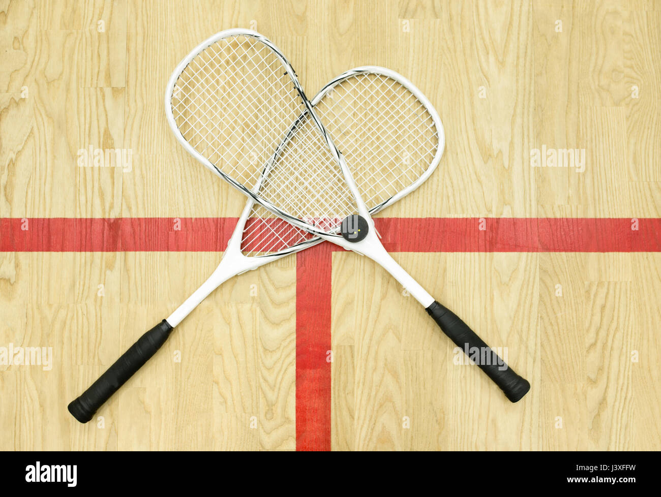 crossed white squash rackets and ball on the floor top view