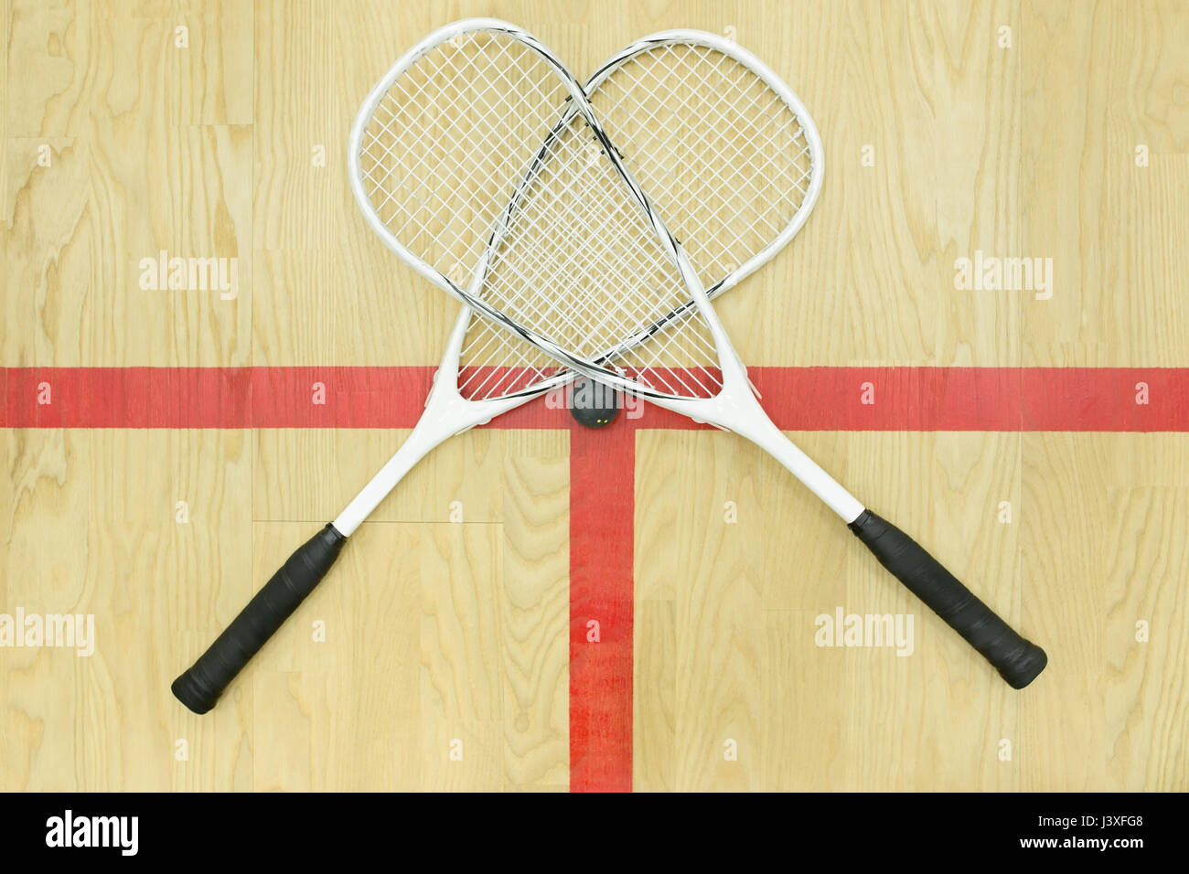 two crossed squash rackets and ball on the wooden floor top view