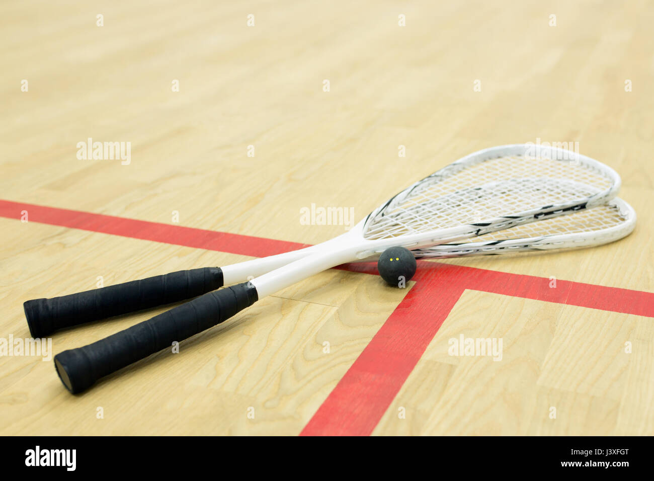 two squash rackets and ball on the wooden floor. Racquetball equipment