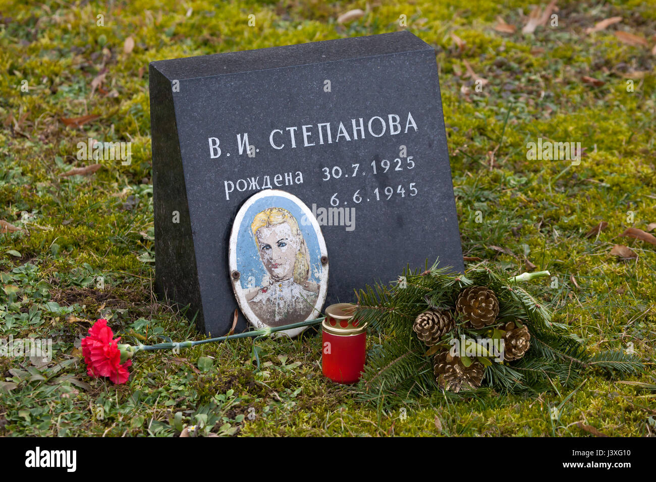 Photograph of Soviet civilian Vera Stepanova on the ground of the Soviet War Memorial at the Central Cemetery in Brno, Czech Republic, pictured on February 9, 2016 after an unsuccessful amateurish restoration. Vera Stepanova was born on July 30, 1925 in Kuznetsk in Penza Region, Russia, served in the Red Army as a typist during World War II and died of typhus at age 19 on June 6, 1945, in Brno in South Moravia, Czechoslovakia. Her photograph installed by the relatives after the war on the mass grave where her body rests was unsuccessfully restored recently by unknown amateurs. Stock Photo