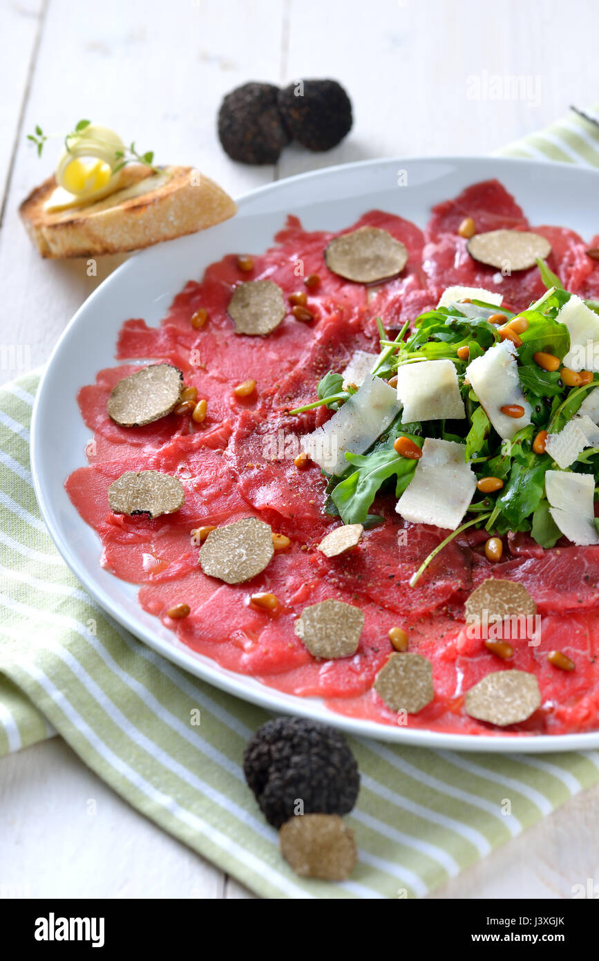 Delicious beef carpaccio with sliced black truffles, rocket salad with