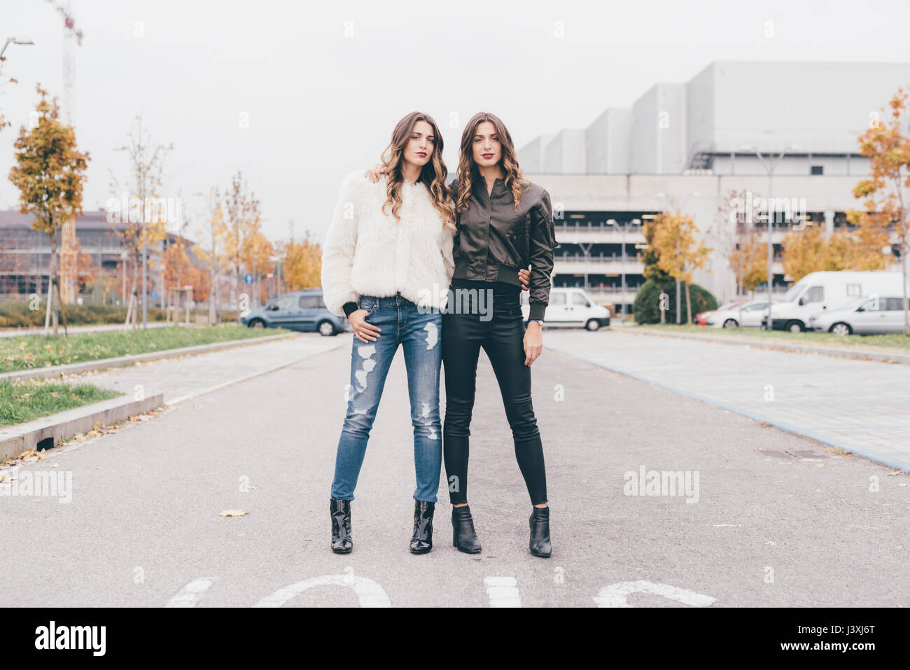 Portrait of twin sisters, in urban area, standing side by side Stock Photo