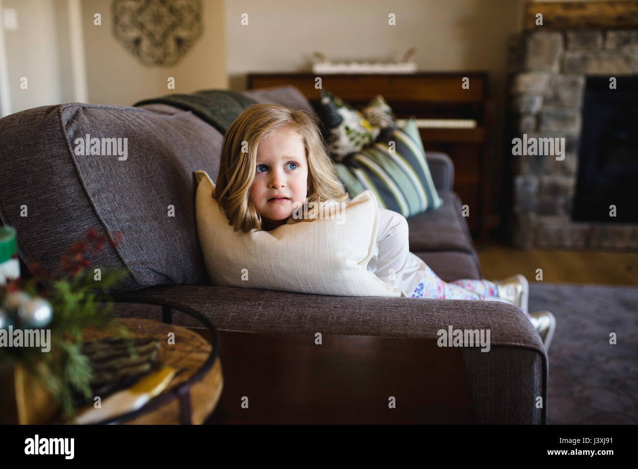 Fearful girl looking sideways from sofa Stock Photo