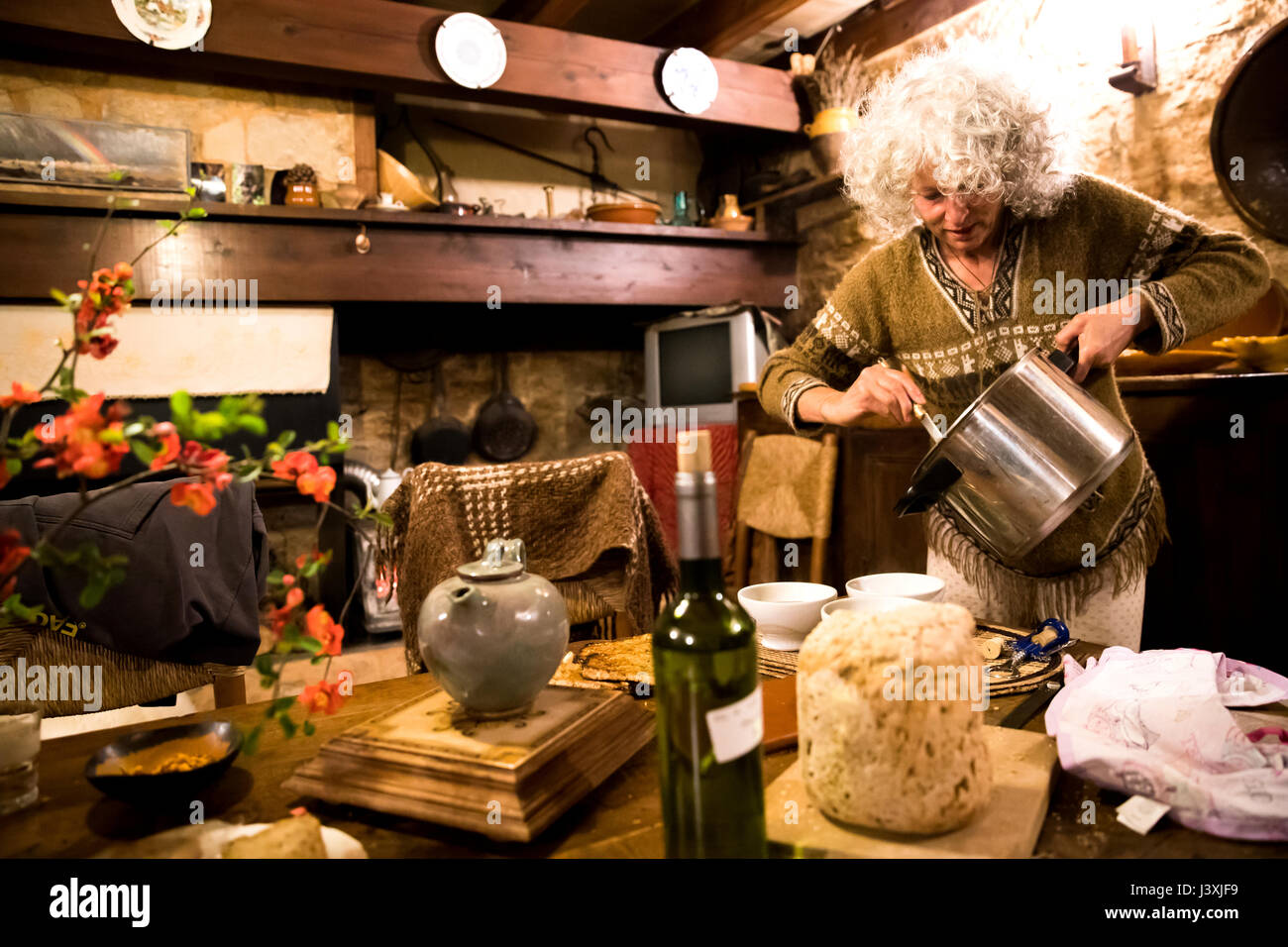Mature woman serving soup in her rustic french kitchen Stock Photo