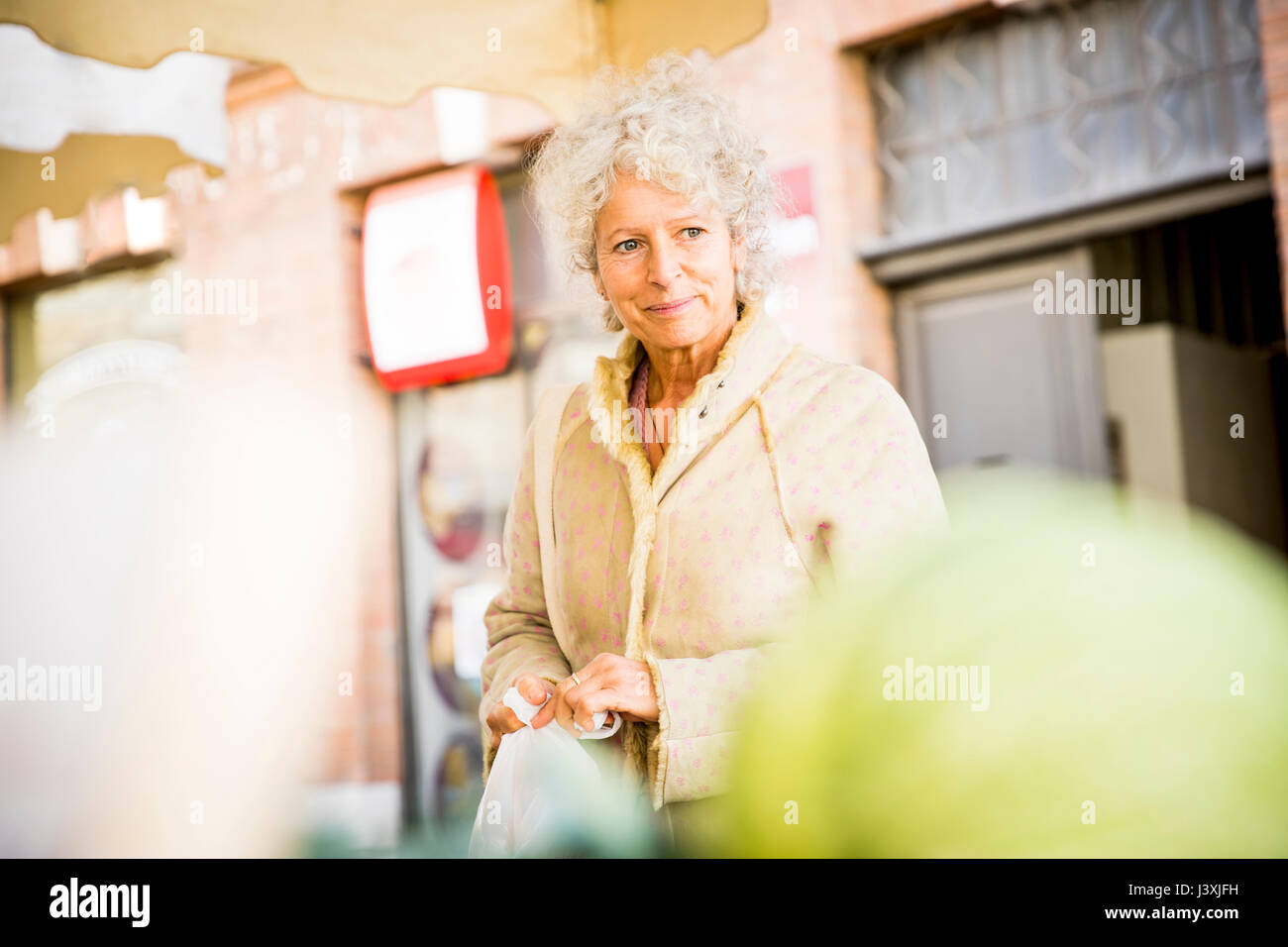 Mature female shopper buying vegetables at local french market Stock Photo