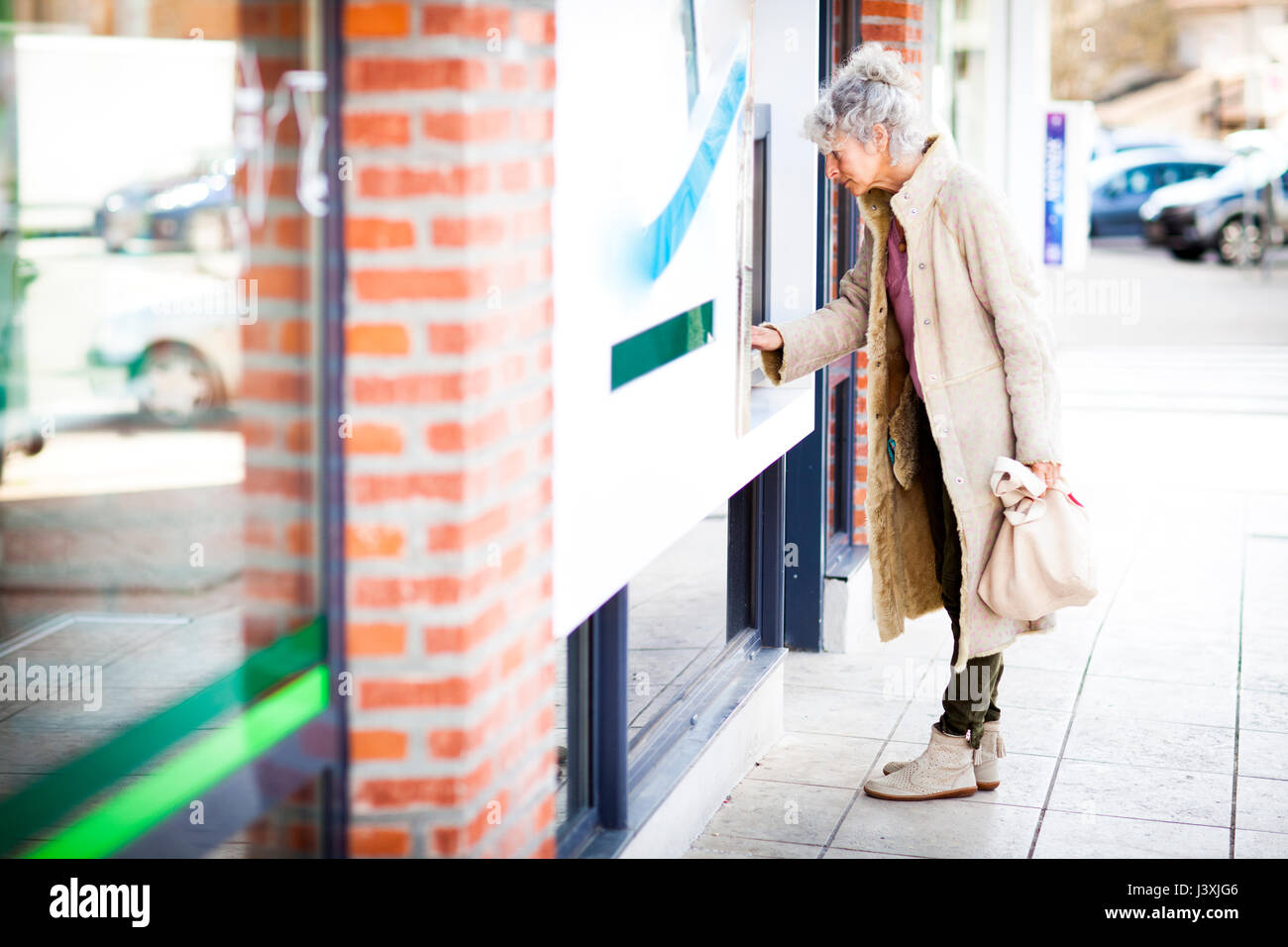 Mature woman using local french cash machine Stock Photo
