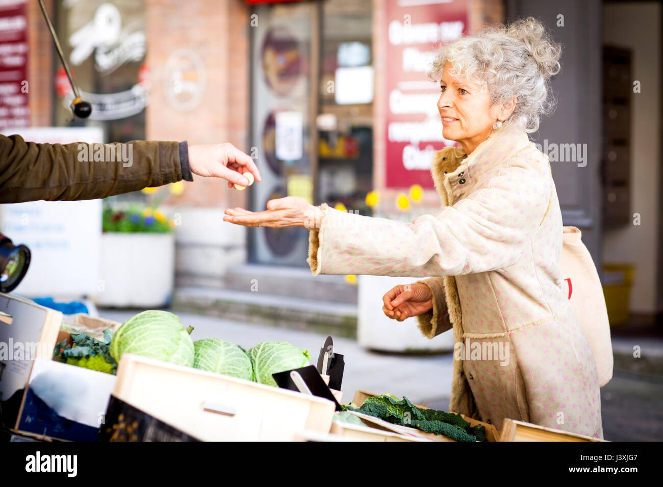 Mature female shopper buying vegetables at local french market Stock Photo