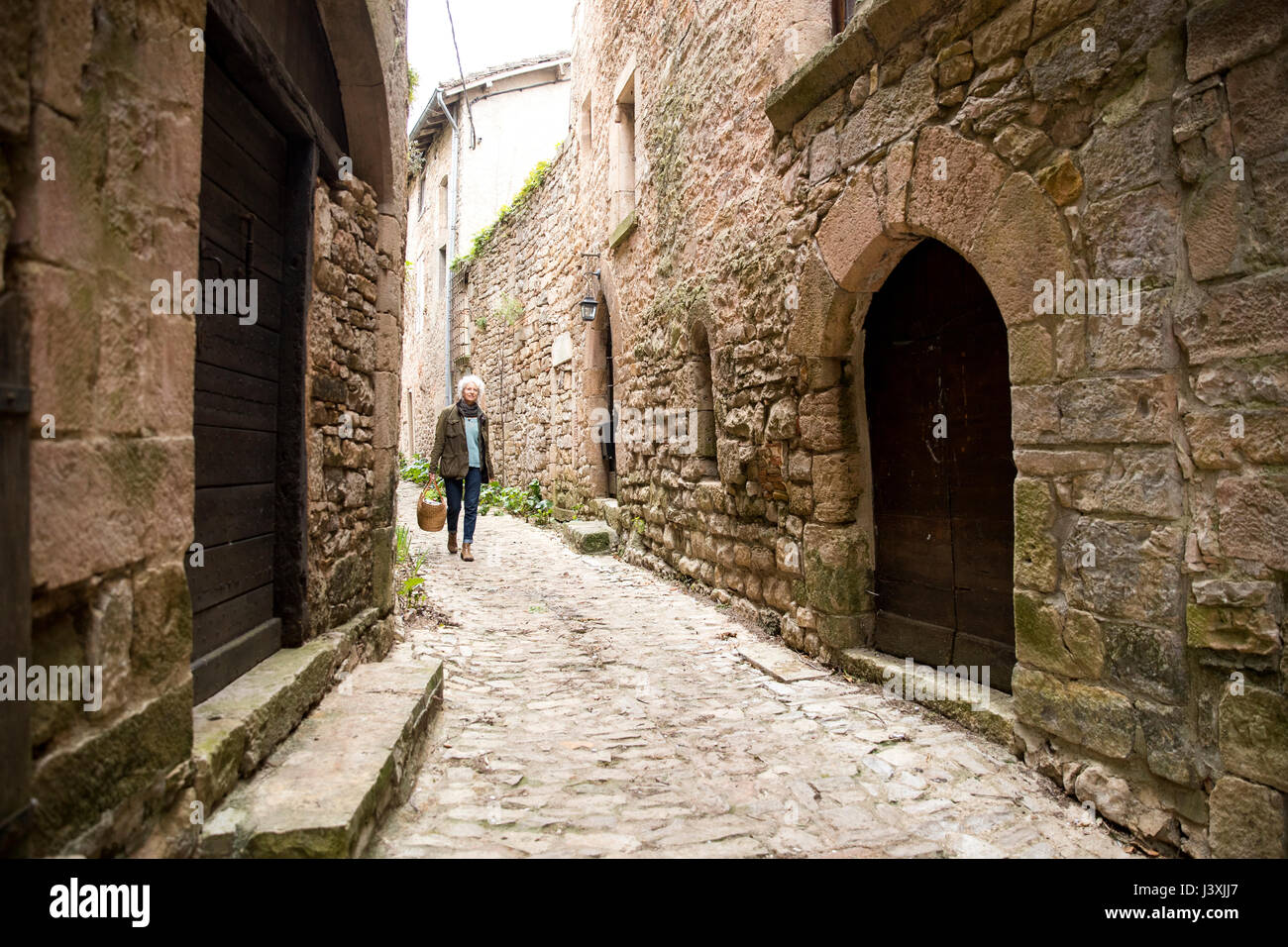 Woman walking in narrow rural street, Bruniquel, France Stock Photo