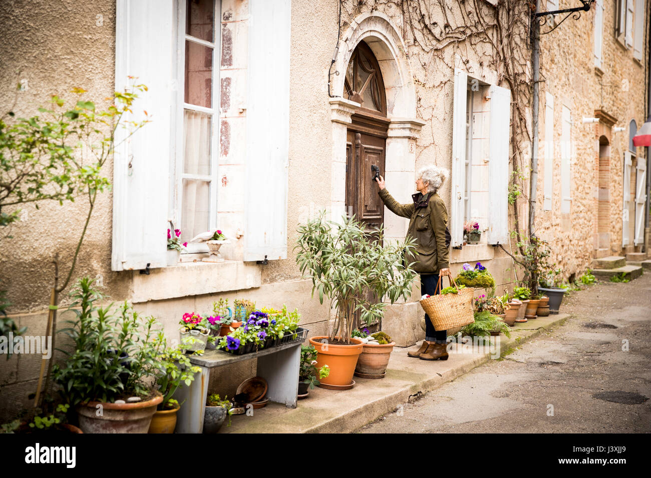 Woman knocking on door, Bruniquel, France Stock Photo
