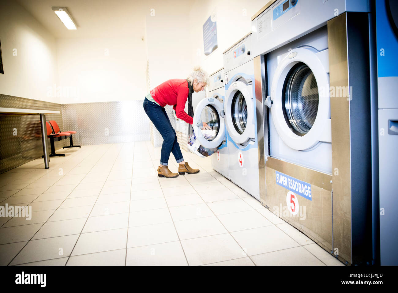 Woman using washing machine in laundrette Stock Photo