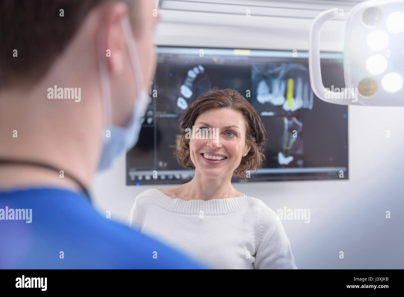 Dentist showing x-rays on screen to patient in dental surgery Stock Photo