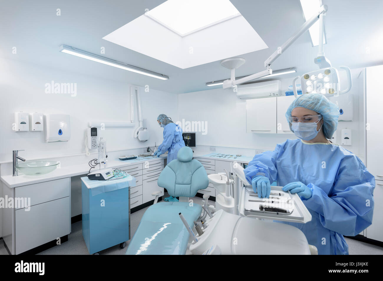 Dentist and assistant preparing in treatment room of dental surgery Stock Photo