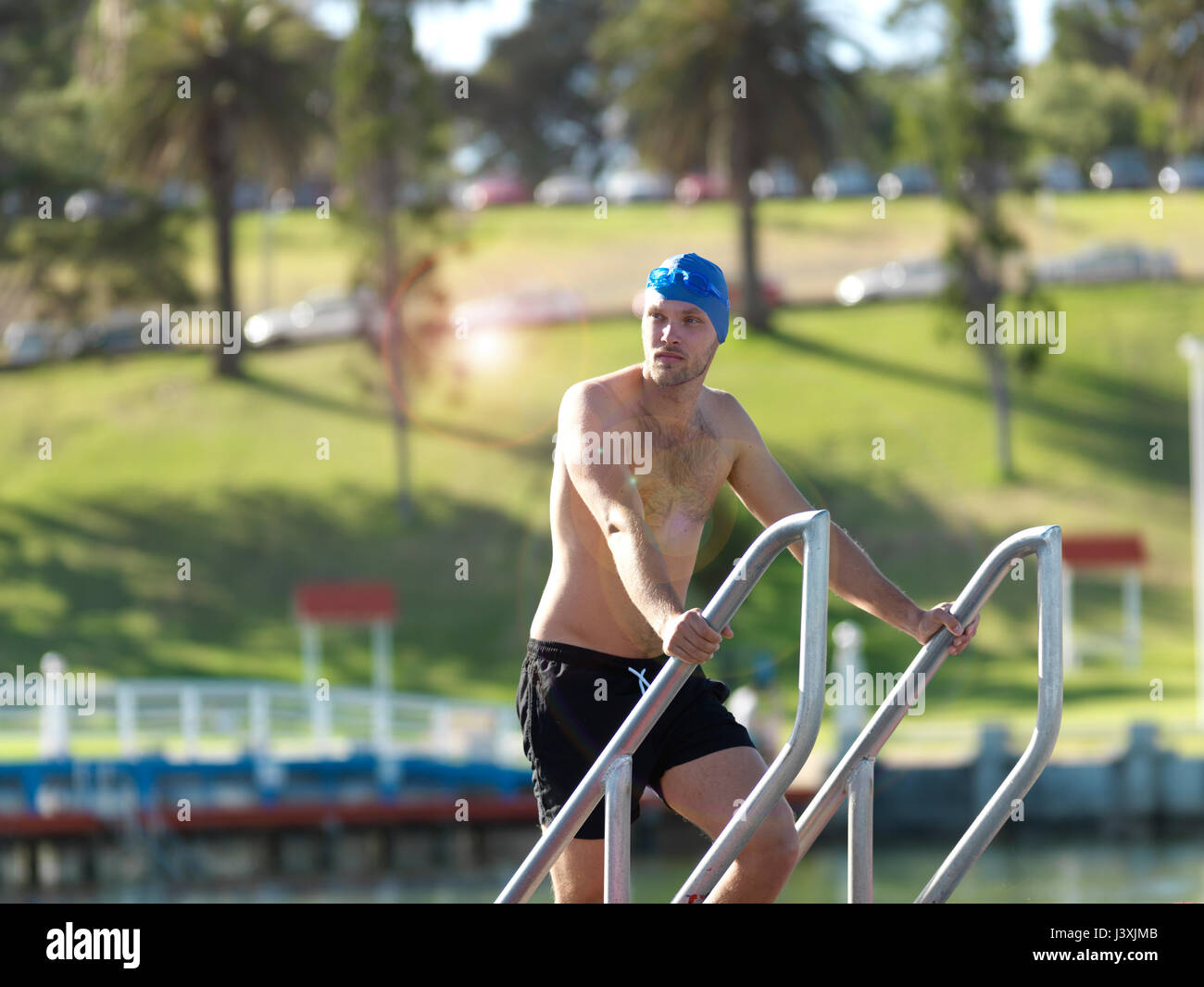 Swimmer coming up from water on ladder, Eastern Beach, Geelong, Victoria, Australia Stock Photo