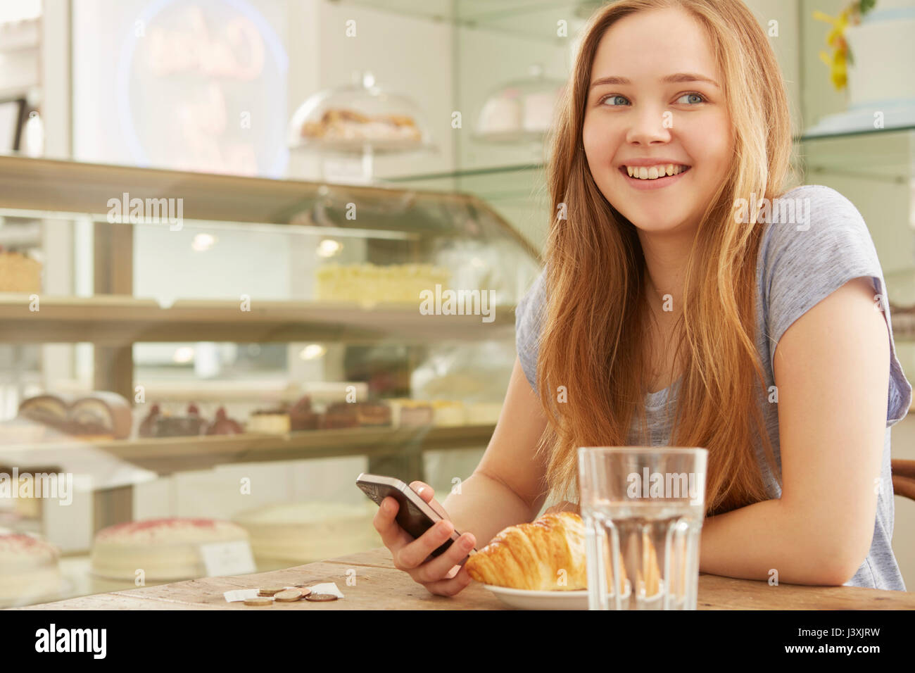 Girl in cafe holding smartphone smiling Stock Photo