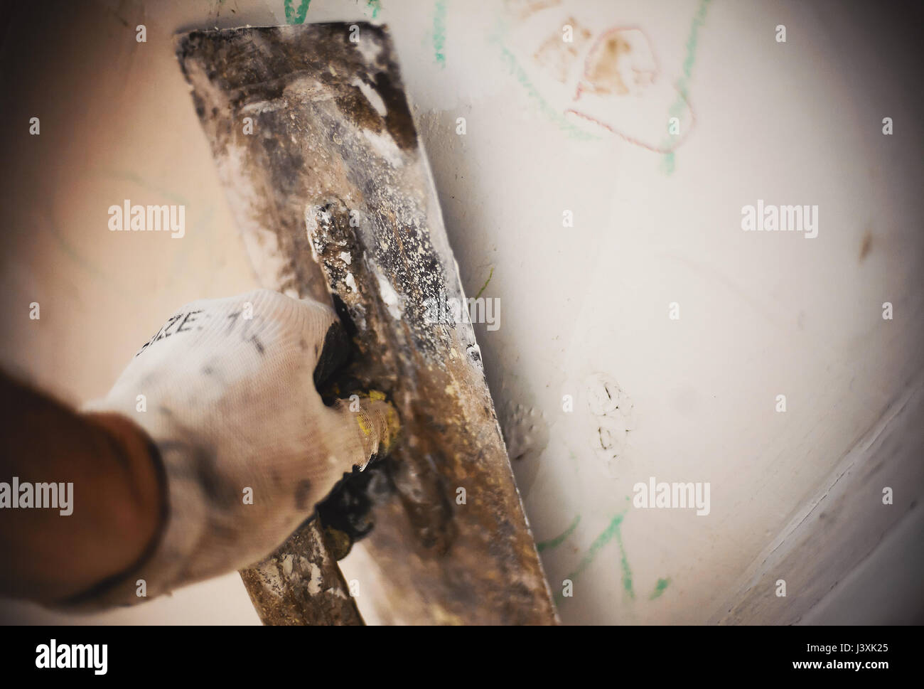 Closeup view on hand holding a tool renovating and old wall. Stock Photo