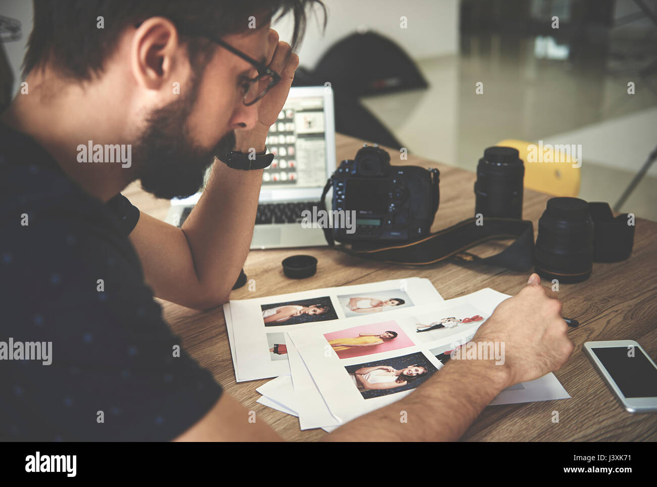 Stressed photographer looking at photographs in photography studio Stock Photo