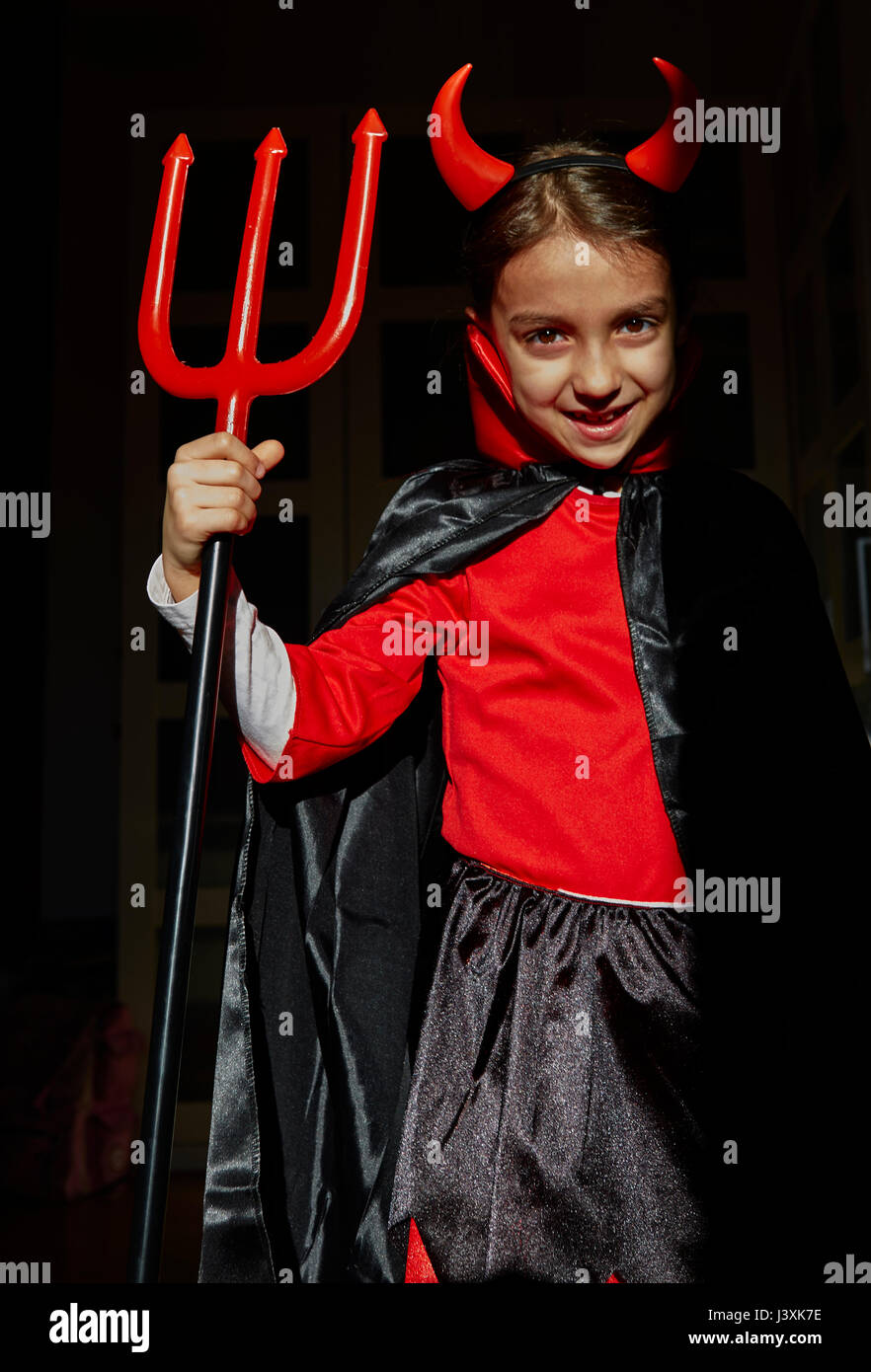 Portrait of girl dressed up as a devil holding a devil's fork Stock Photo
