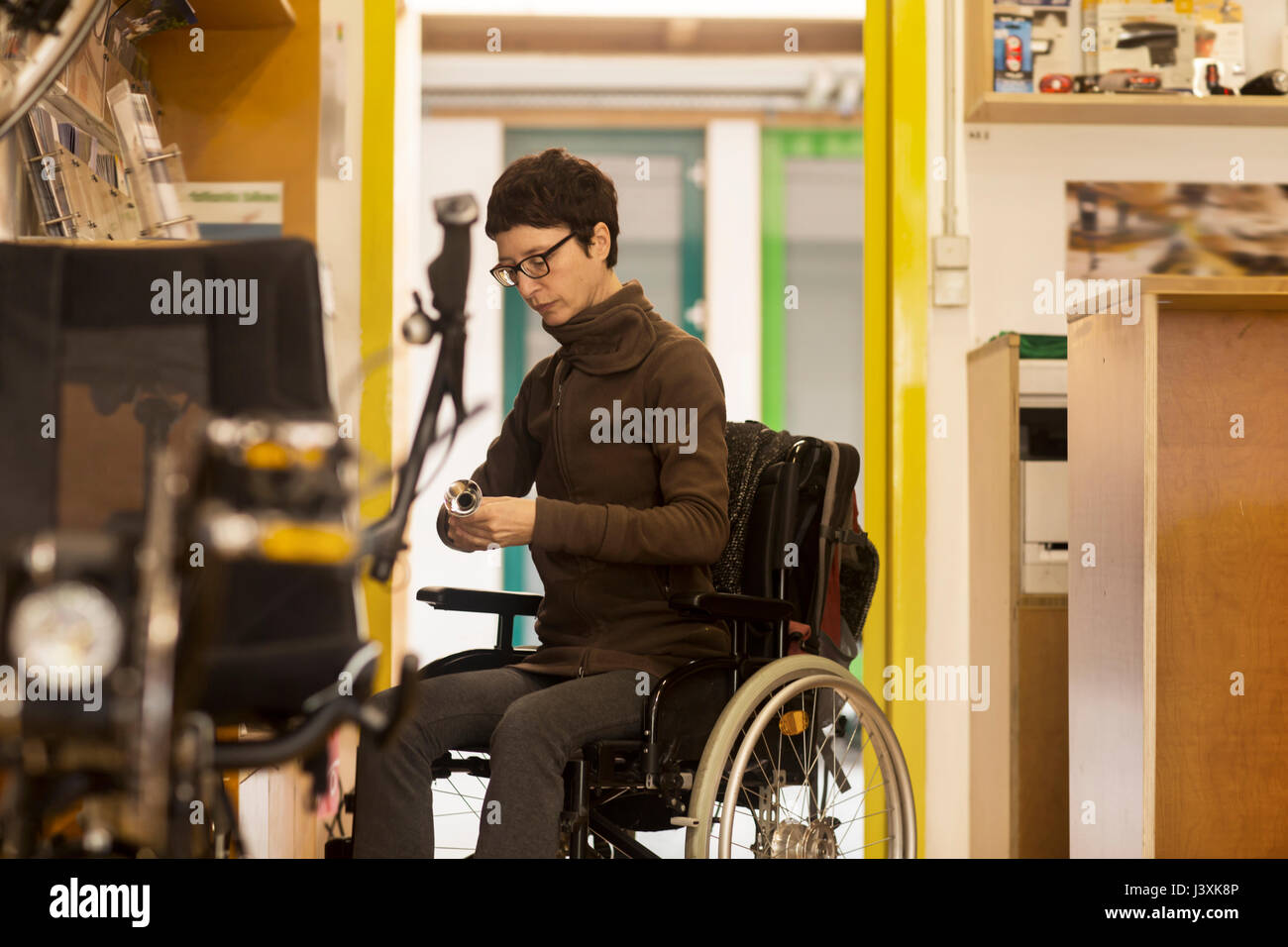 Woman in wheelchair in bicycle repair shop Stock Photo Alamy