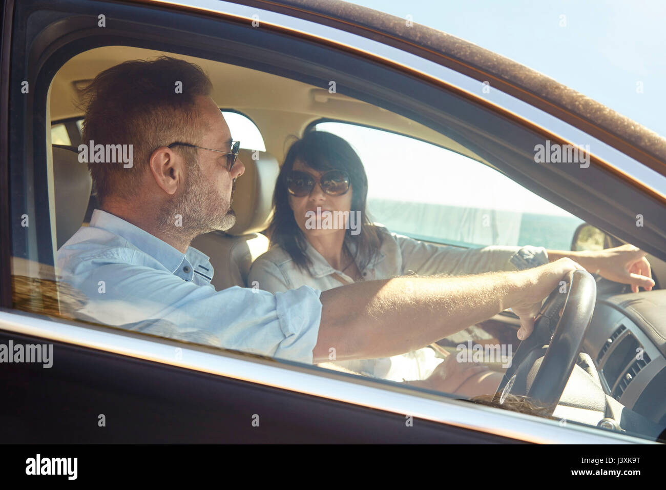Couple in car, man driving, woman pointing ahead Stock Photo