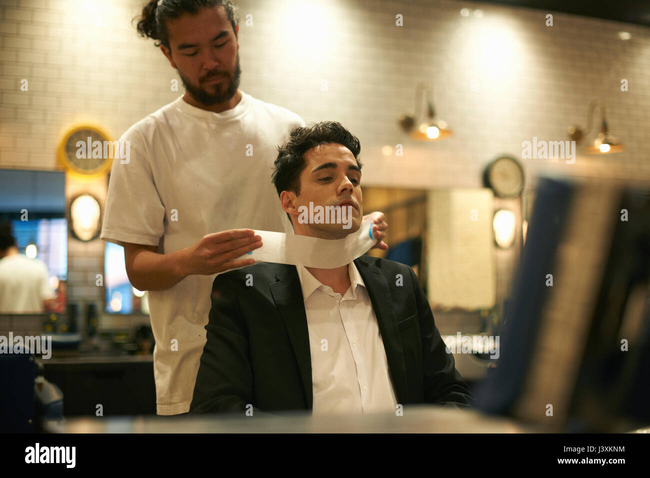 Barber preparing businessman for shave in barber shop Stock Photo Alamy