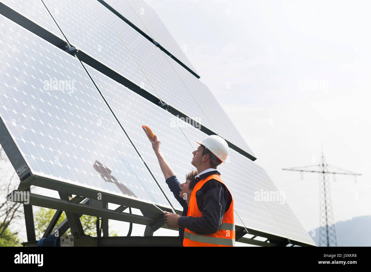 Male and female engineers using multimeter on solar panels Stock Photo