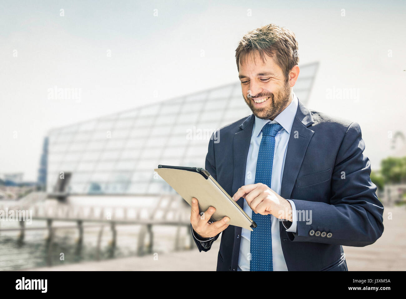 Businessman using digital tablet touchscreen on city waterfront Stock ...