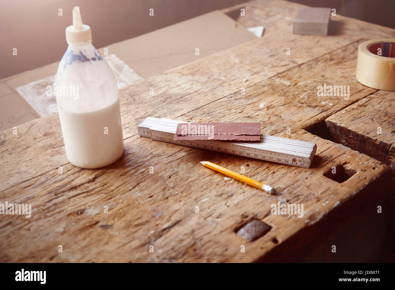 Carpenter's workbench with glue, sandpaper and tape measure Stock Photo