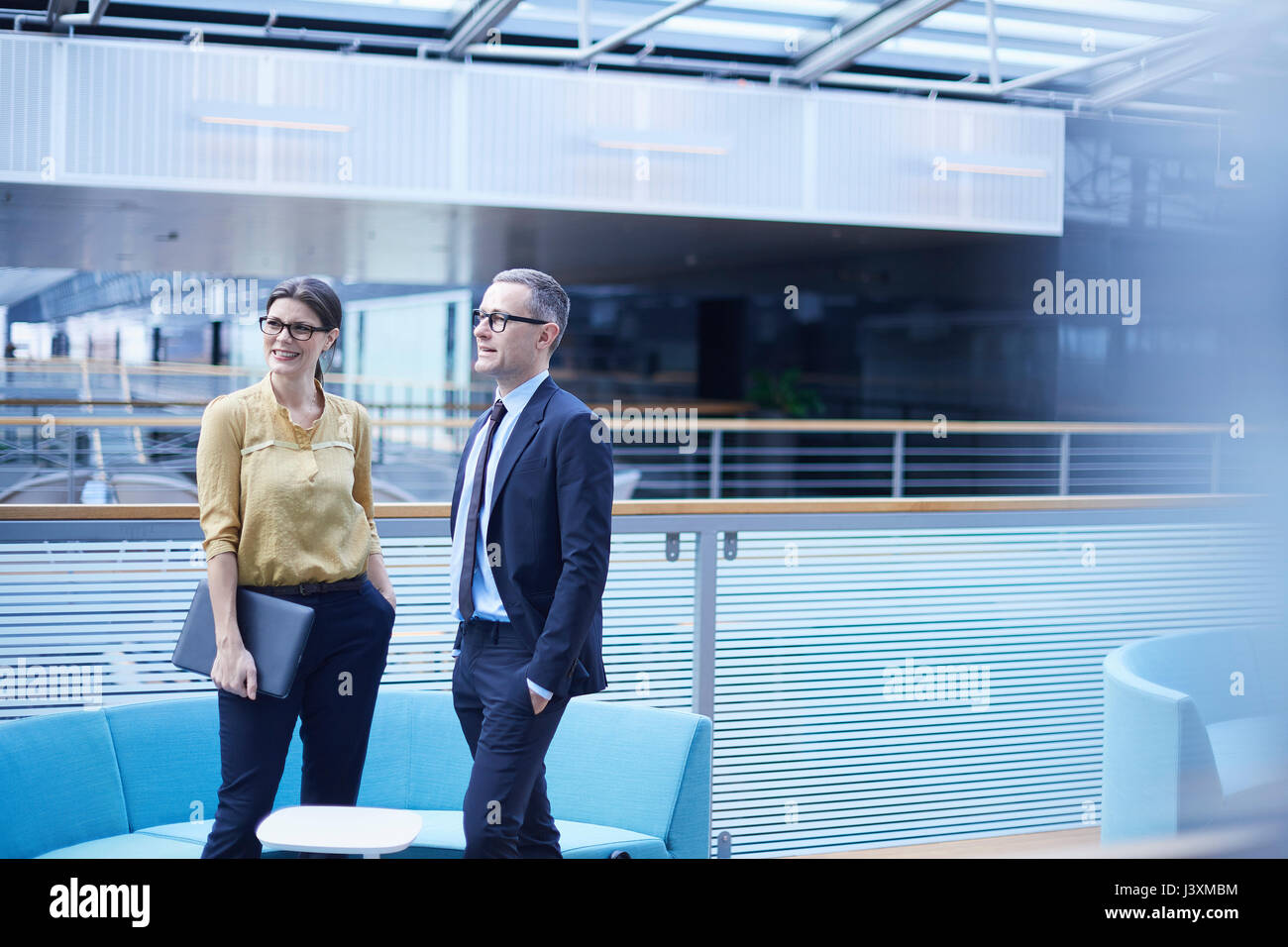 Businessman and woman standing in office atrium Stock Photo - Alamy