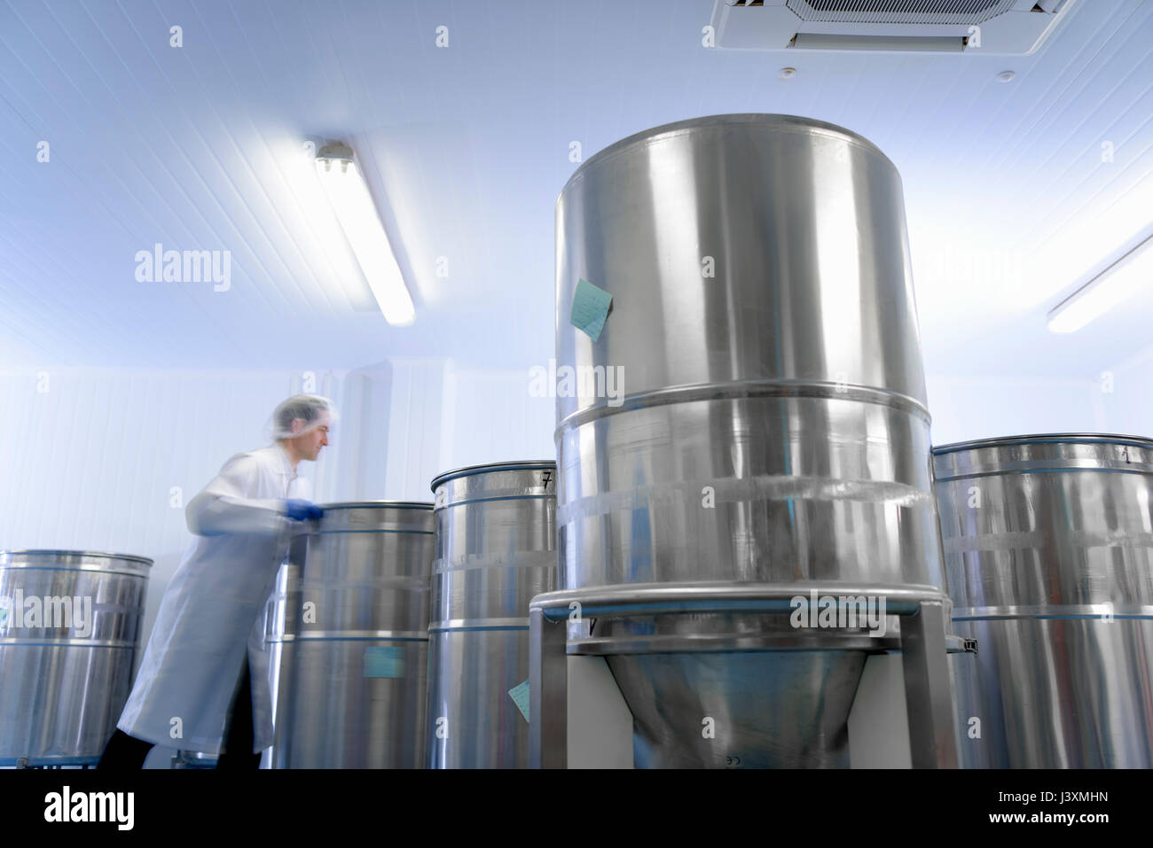Worker moving vat in pharmaceutical factory Stock Photo