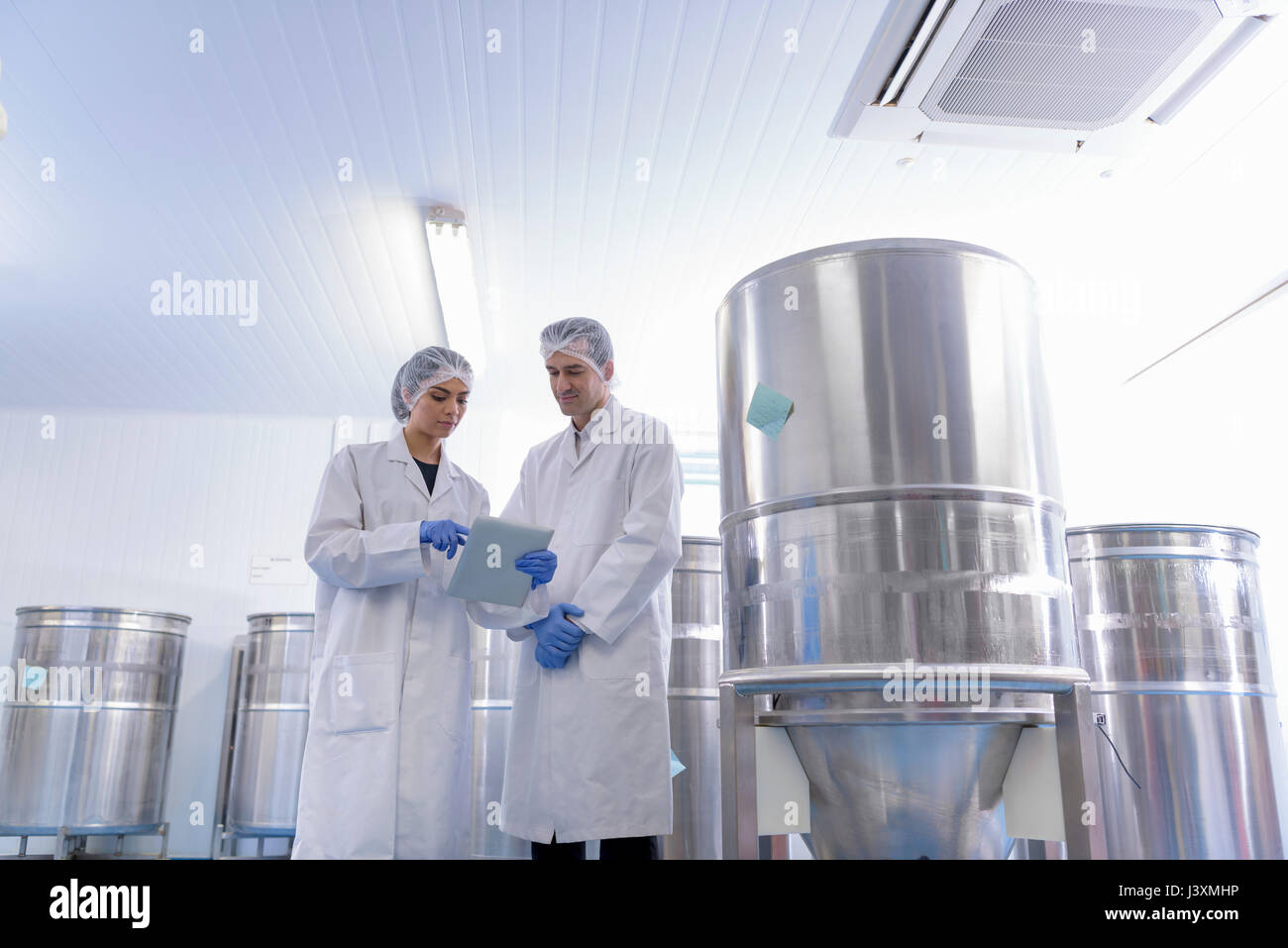 Worker in discussion by vat in pharmaceutical factory Stock Photo