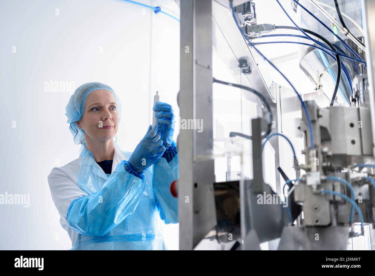 Worker with gel filling machine in pharmaceutical factory Stock Photo