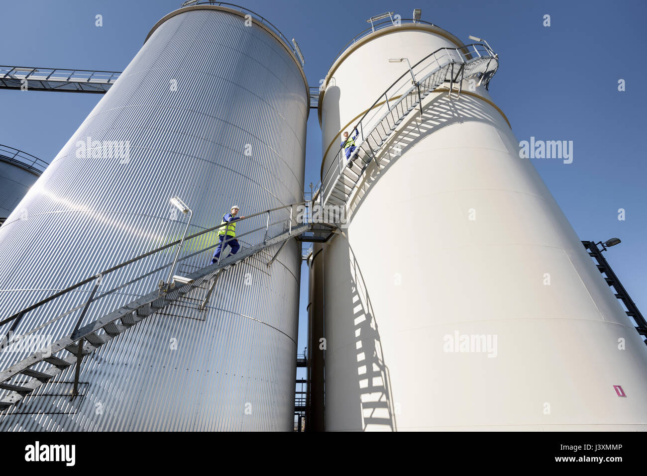 Workers climbing oil storage tanks in oil blending factory Stock Photo