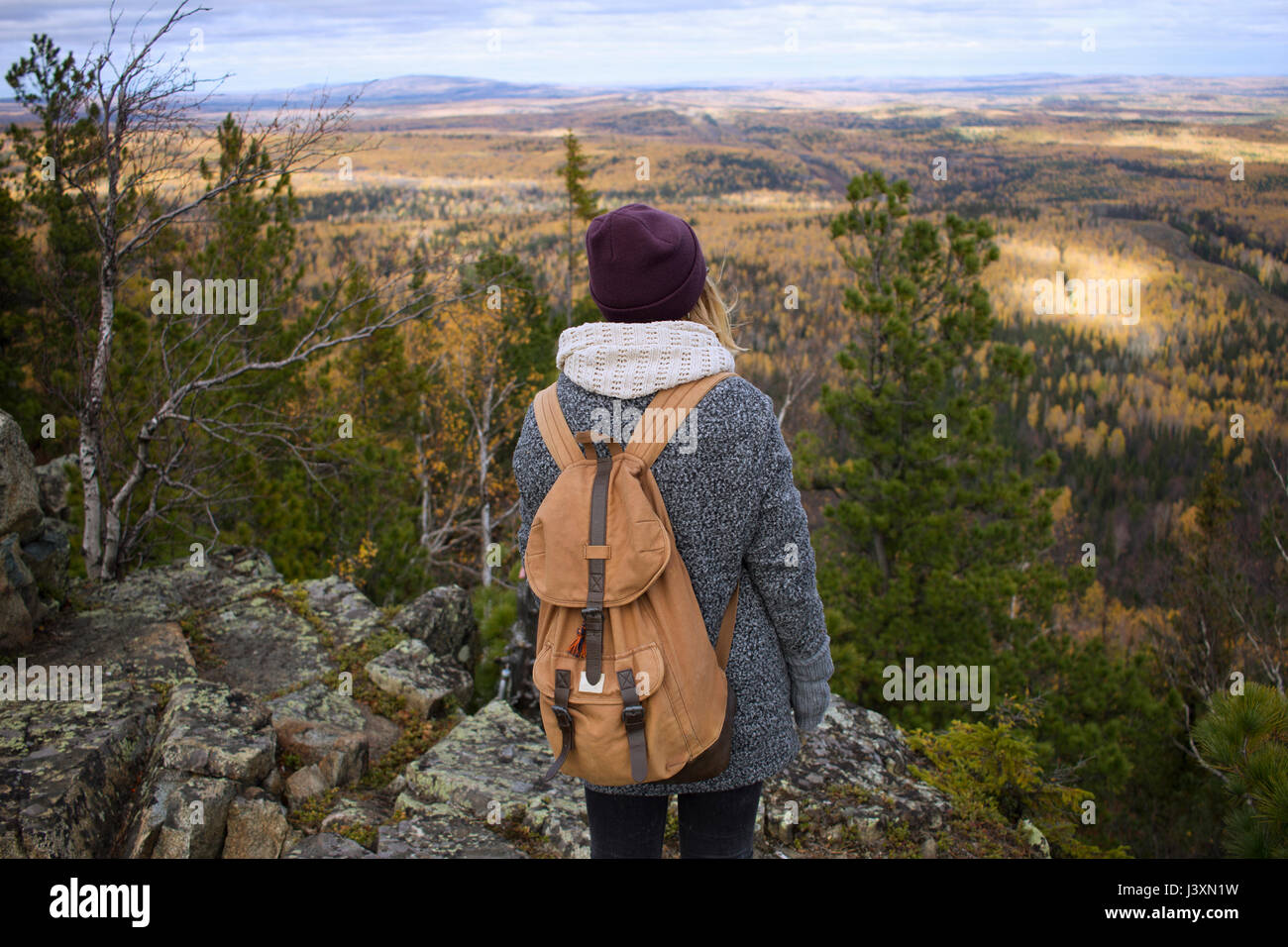 Young woman standing on mountainside, looking at view, Sverdlovsk Oblast, Russia Stock Photo
