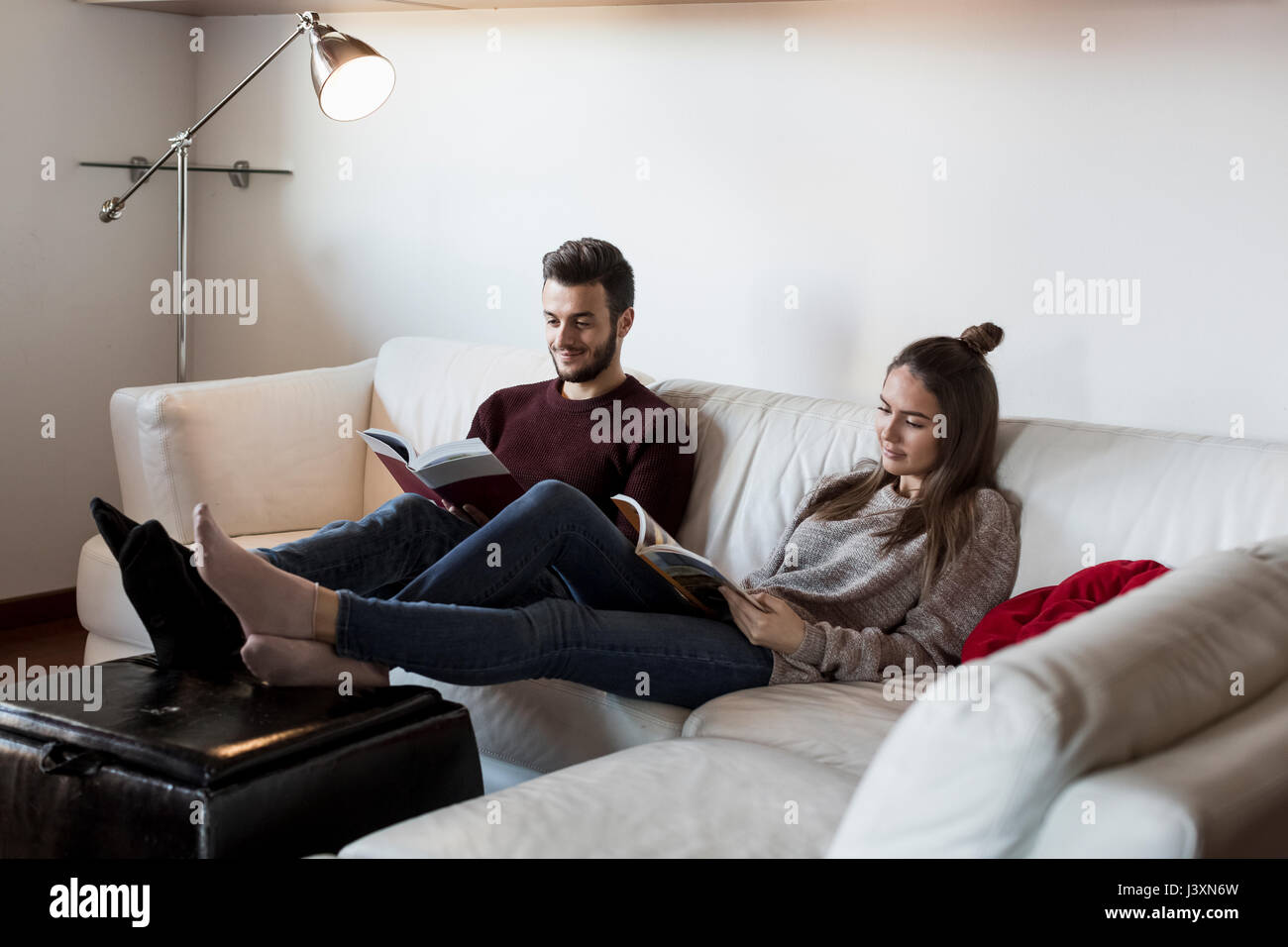 Young couple, relaxing on sofa, reading magazines Stock Photo - Alamy