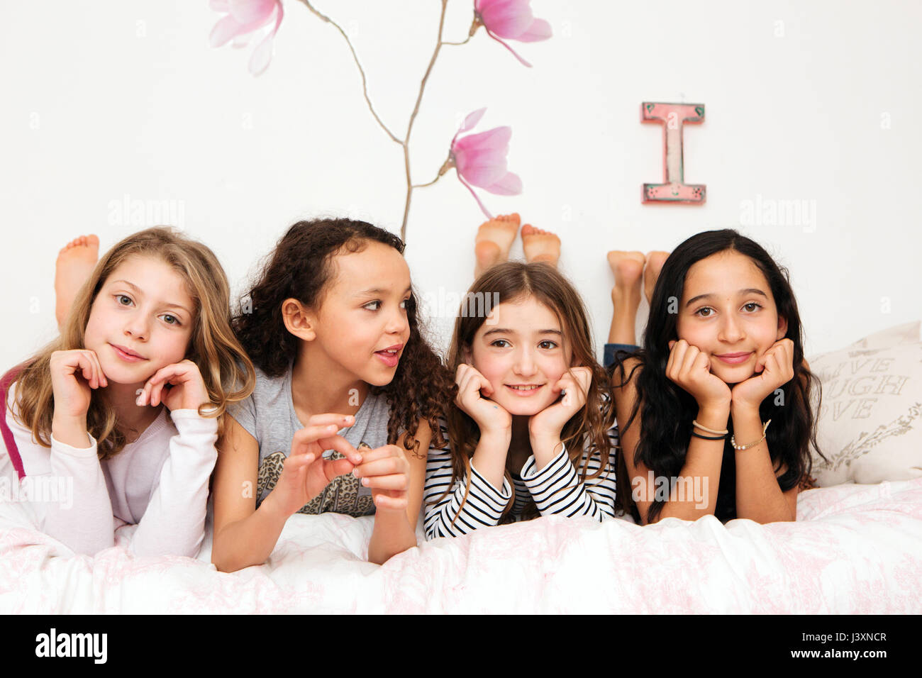 Girls Lying On Bed Resting On Elbows Looking At Camera Stock Photo Alamy