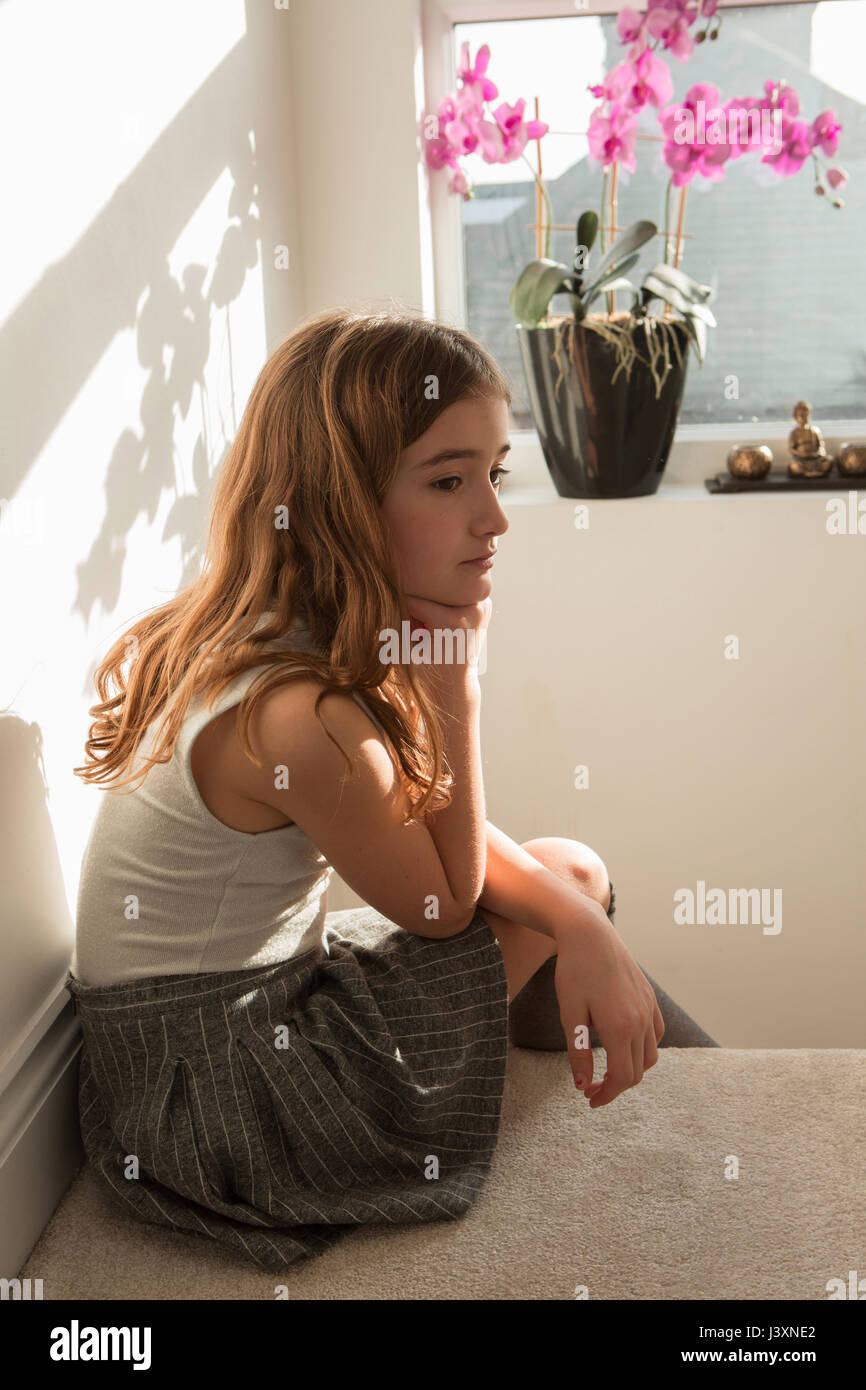 Girl sitting on top of stairs looking sad Stock Photo